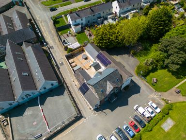 An aerial view of buildings with solar panels a parking lot with cars a playground and green areas at Teifi Villa in St Dogmaels