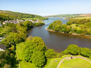 A river flowing through a green landscape with trees houses and hills at Teifi Villa in St Dogmaels