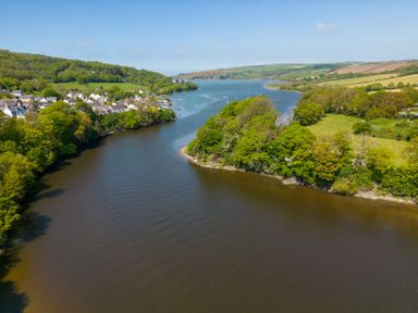 A river flowing between green hills and a small village at Teifi Villa in St Dogmaels