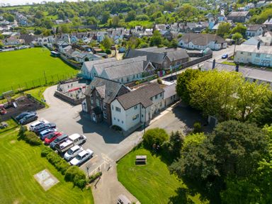 An aerial view of a residential area with houses school playground and cars parked near green fields at Teifi Villa in St Dogmaels