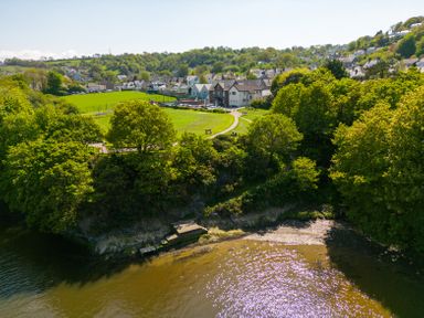 A riverside park with trees and walking paths near houses in a residential area at Teifi Villa in St Dogmaels