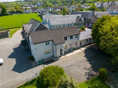 A two story building with a parking area in front and a green field behind at Teifi Villa in St Dogmaels