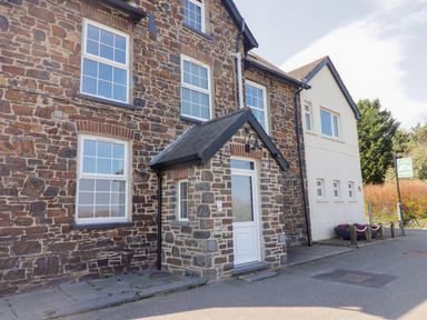 The exterior of a stone and white building with multiple windows and a small porch at Teifi Villa in St Dogmaels