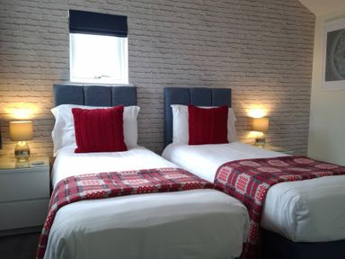 A bedroom with two single beds and lamps at Teifi Villa St Dogmaels