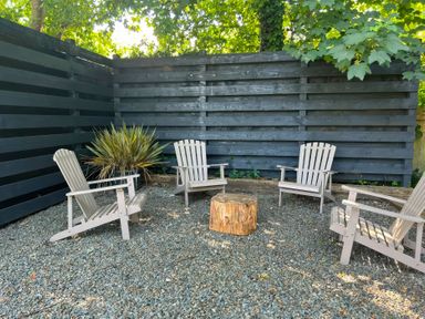 A garden area with chairs and a stump at Teifi Villa in St Dogmaels