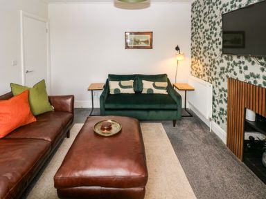 A living room with a green sofa and coffee table at Teifi Villa in St Dogmaels