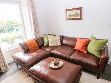 A living room with a brown leather sofa and pillows at Teifi Villa in St Dogmaels