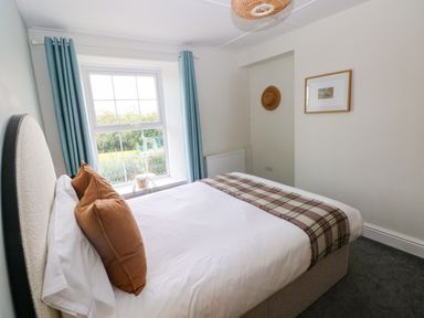 A bedroom with a bed and window at Teifi Villa in St Dogmaels