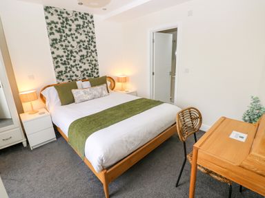 A bedroom with a bed, bedside tables, a desk, and a chair at Teifi Villa St Dogmaels