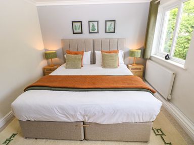 A bedroom with a bed, nightstands, lamps, and a window at Teifi Villa in St Dogmaels