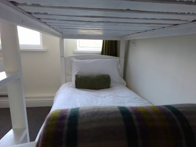 A bed with a pillow and cushion beside a window at Teifi Villa St Dogmaels