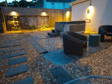 A garden with a hot tub and seating area at Teifi Villa in St Dogmaels