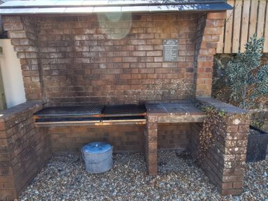 An outdoor grill setup with a brick wall and metal buckets at Teifi Villa in St Dogmaels