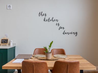 A dining table with four chairs placemats and a plant with kitchen decor on the wall at Foxes Den in Allerston near Thornton Dale