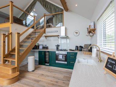 A kitchen with green cabinets a wooden staircase and a window with blinds at Foxes Den Allerston near Thornton Dale