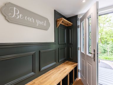 An entryway with a wooden bench and wall hooks and a sign that says Be our guest at Foxes Den in Allerston near Thornton Dale