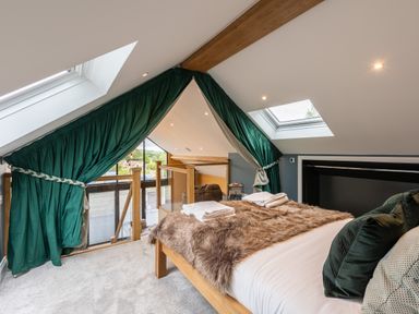 A bedroom with a bed covered in fur blankets green curtains and skylight windows at Foxes Den in Allerston near Thornton Dale