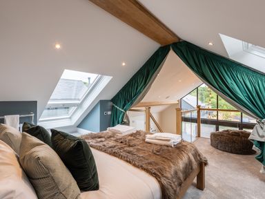 A bedroom with a bed covered with a fur blanket and pillows near a skylight window and green curtains at Foxes Den in Allerston near Thornton Dale