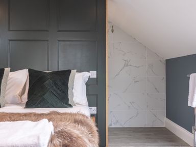 A bed with green pillows and folded blankets next to a sloped ceiling tiled wall at Foxes Den Allerston near Thornton Dale