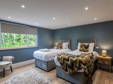 A bedroom with two single beds a bedside table and a window showing greenery at Foxes Den in Allerston near Thornton Dale