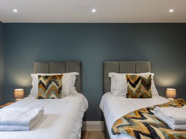 A bedroom with two single beds with patterned cushions and folded towels at Foxes Den Allerston near Thornton Dale