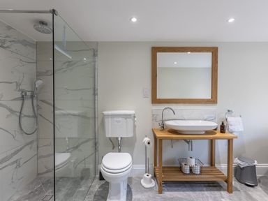 A bathroom with a glass enclosed shower a toilet a wooden vanity with a sink and a mirror at Foxes Den Allerston near Thornton Dale