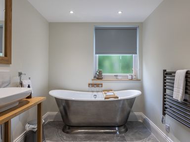 A bathroom with a metal freestanding bathtub under a window with a roller blind at Foxes Den in Allerston near Thornton Dale