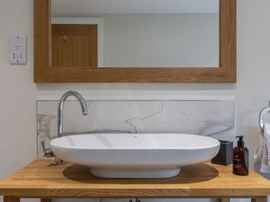 A bathroom sink with a faucet soap dispenser and a mirror at Foxes Den in Allerston near Thornton Dale
