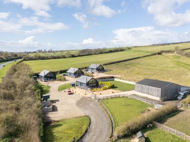 A group of four houses with driveways and a large barn in a rural area at Foxes Den in Allerston near Thornton Dale