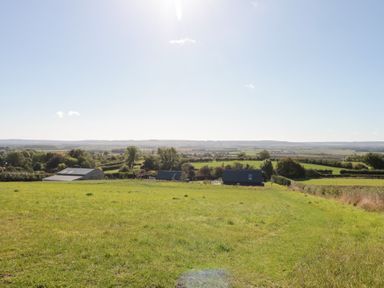 A landscape view with grass, trees and buildings at Foxes Den Allerston near Thornton Dale