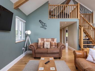 A living room with leather sofas a wooden coffee table a floor lamp and a staircase at Eagles Peak in Allerton near Thornton-Le-Dale