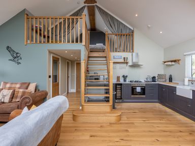 An open plan living space with a staircase leading to a loft bedroom a kitchen with cabinets and appliances and sofas in Eagles Peak in Allerton near Thornton-Le-Dale