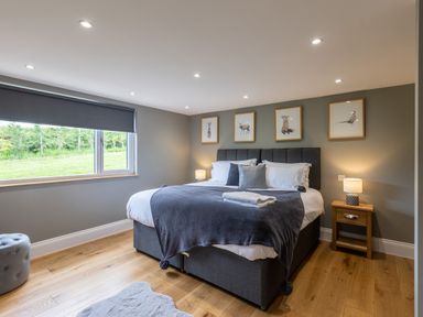 A bedroom with a large bed bedside tables lamps and animal pictures on the wall at Eagles Peak in Allerton near Thornton-Le-Dale