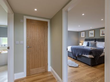 A hallway with a wooden door and a bedroom with a bed with cushions and animal pictures on the wall at Eagles Peak in Allerton near Thornton-Le-Dale