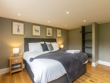 A bedroom with a bed side table lamps animal pictures on the wall and wooden flooring at Eagles Peak in Allerton near Thornton-Le-Dale