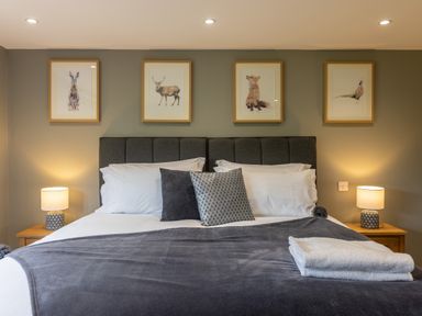 A bedroom with a bed pillows bedside tables lamps and animal artwork at Eagles Peak in Allerton near Thornton-Le-Dale