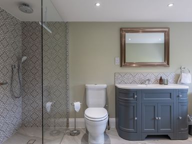 A bathroom with a toilet a grey vanity with a sink and mirror and a glass shower enclosure at Eagles Peak in Allerton near Thornton-Le-Dale