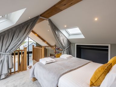A bedroom with a bed and yellow pillows next to a staircase and skylights at Eagles Peak in Allerton near Thornton-Le-Dale