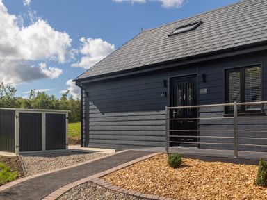 Exterior of a dark grey house with a sloped roof and a small garden area at Eagles Peak in Allerton near Thornton-Le-Dale