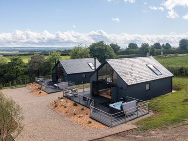 Two modern dark-colored houses with large windows and decks in a rural setting at Eagles Peak in Allerton near Thornton-Le-Dale