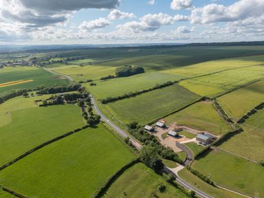 An aerial view of green fields with a road and several buildings in a rural area at Eagles Peak in Allerton near Thornton-Le-Dale