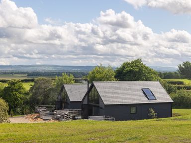 Two modern black cabins with large windows and outdoor seating on a grassy hill at Eagles Peak in Allerton near Thornton-Le-Dale