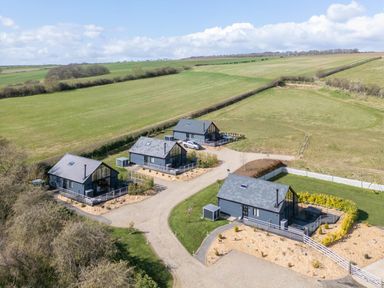 Four gray houses with yards and driveways surrounded by green fields at Eagles Peak in Allerton near Thornton-Le-Dale