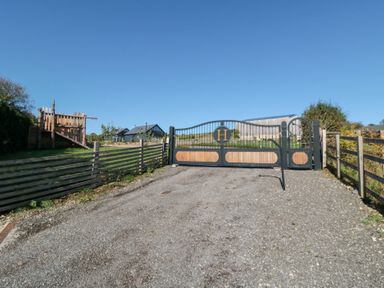 A gated entrance with a gravel driveway and play structure at Eagles Peak in Allerton near Thornton-Le-Dale