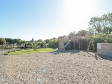 An outdoor play area with a playhouse and swings at Eagles Peak in Allerton near Thornton-Le-Dale