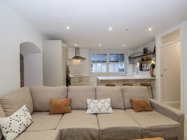 A living room with a large beige sectional sofa and a kitchen with a white island and stools at Dixon Court in Ambleside