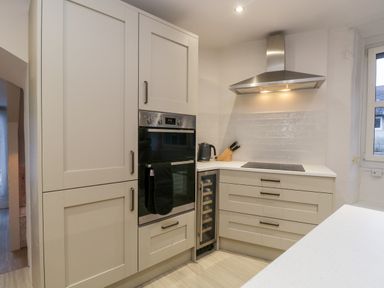 A kitchen with built in oven, stovetop, extractor hood, wine cooler, kettle, and knives at Dixon Court in Ambleside