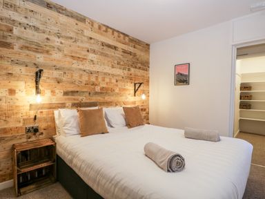 A bedroom with a double bed and wooden wall paneling at Dixon Court in Ambleside