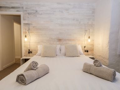 A bedroom with a double bed with pillows and rolled towels on the bed at Dixon Court in Ambleside