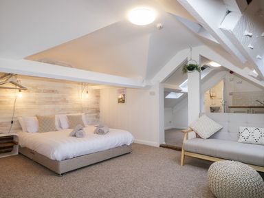 A bedroom with a double bed pillows sofa and a pouf at Dixon Court in Ambleside